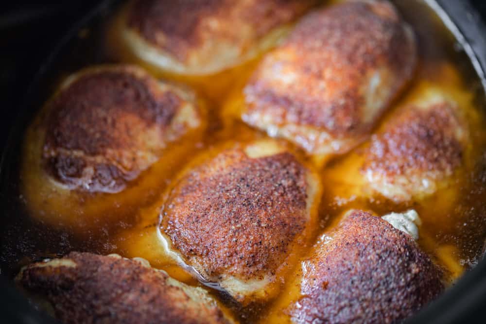 close up of seasoned chicken thighs in a slow cooker