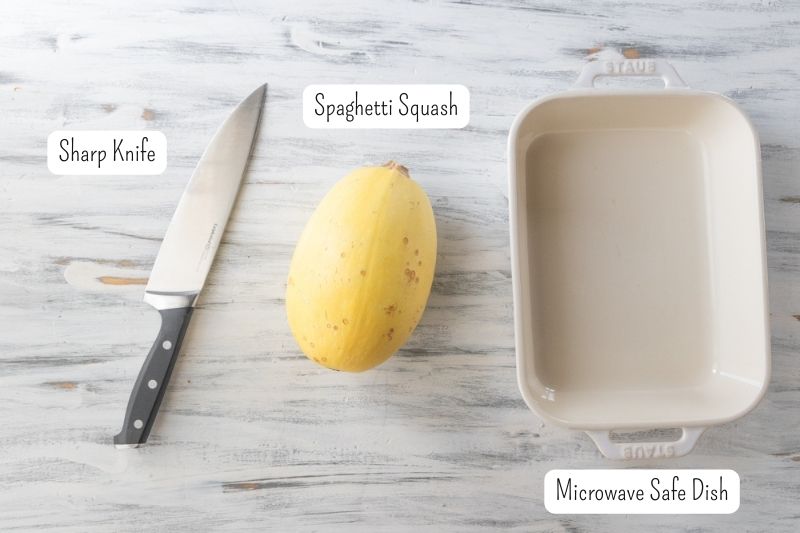 sharp knife, whole spaghetti squash and a microwave safe dish on a countertop