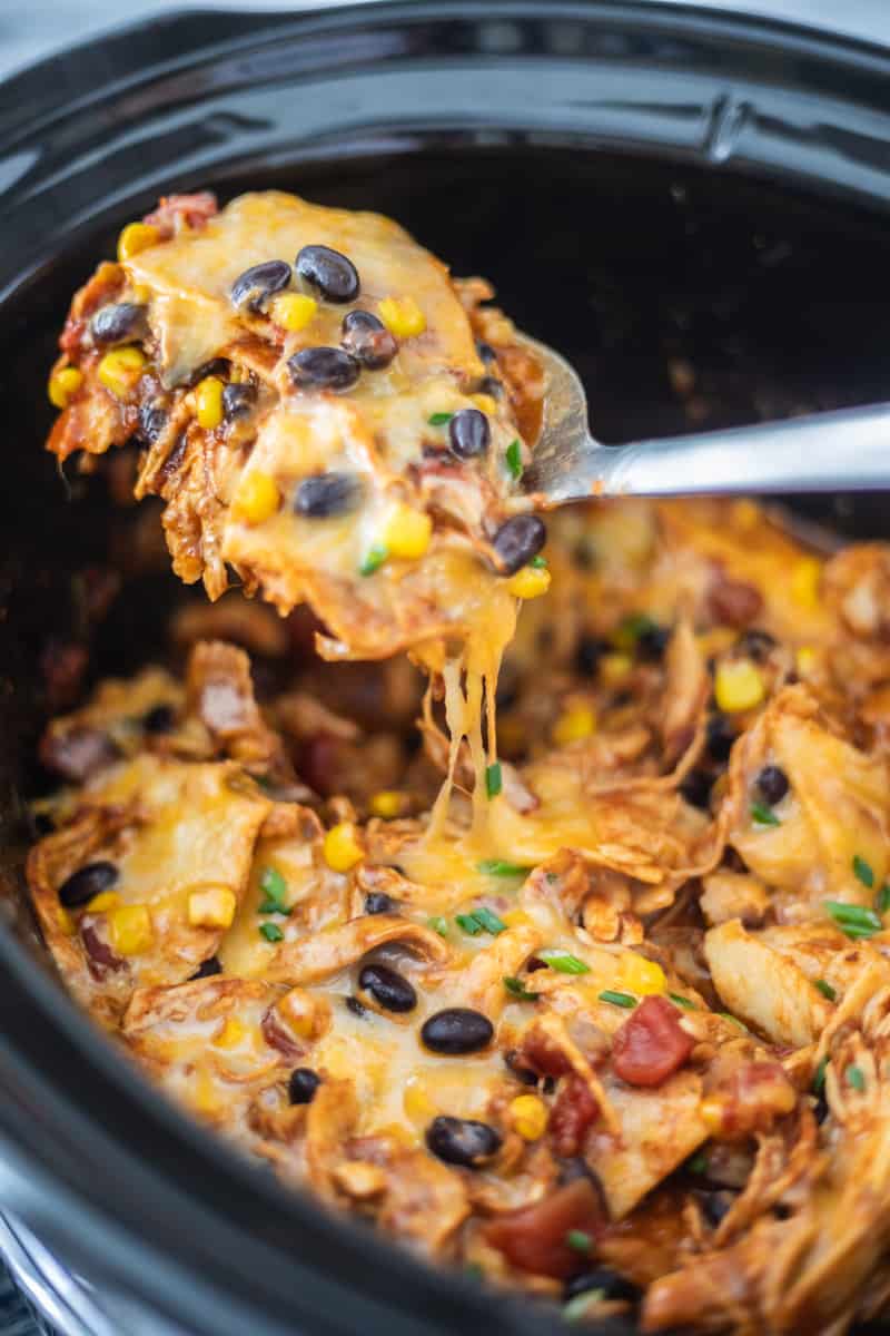 chicken enchilada casserole in a crockpot with a spoon