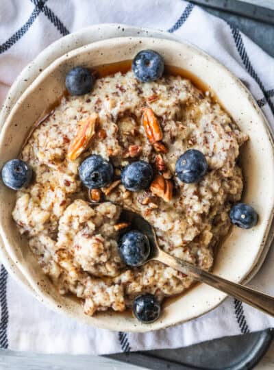 top down shot of a bowl of oatmeal topped with syrup, nuts and blueberries