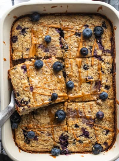 a top down view of baked oatmeal with blueberries on top in a casserole dish