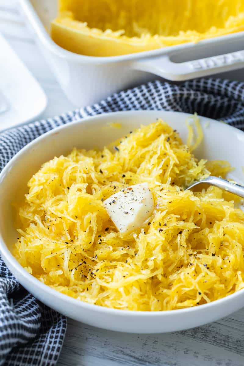 spaghetti squash in bowl topped with salt, pepper and butter