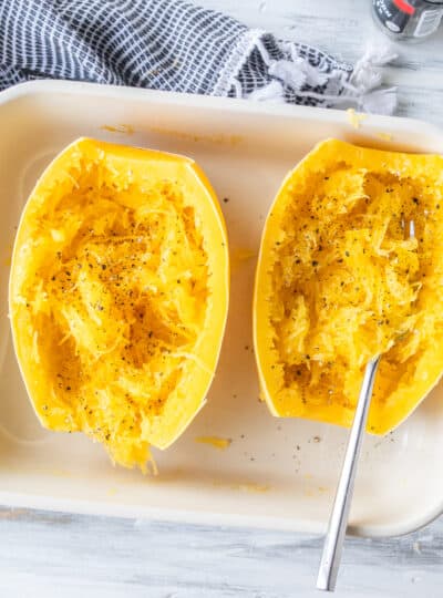 cooked spaghetti squash in a pan with freshly cracked pepper and a fork