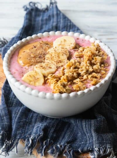 a high protein smoothie bowl with peanut butter, sliced bananas and granola on top