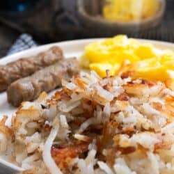 up close pic of hashbrowns on a plate with eggs and sausage
