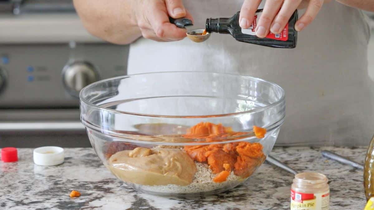 vanilla being added to a bowl of ingredients