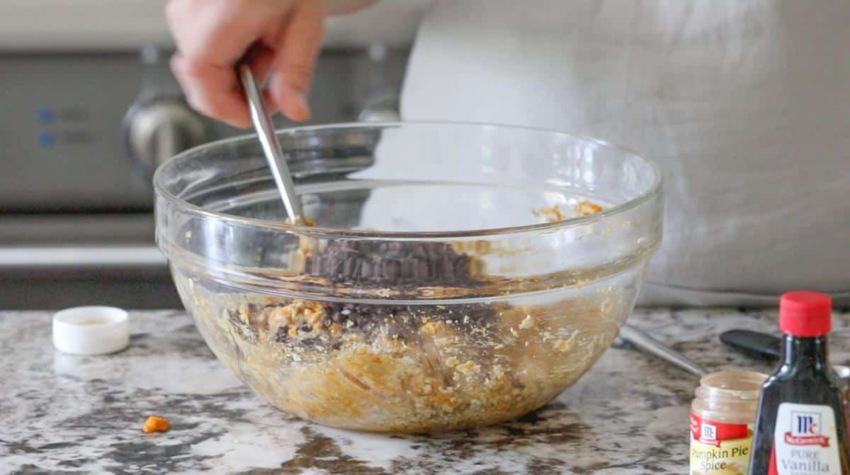 chocolate chips added to a bowl with oats and peanut butter mixture