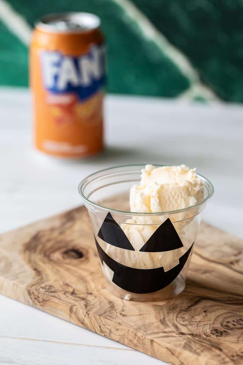vanilla ice cream in a cup with a halloween jack o lantern face sticker on it