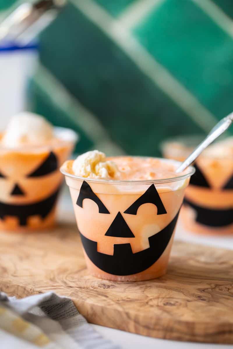a jack o lantern float in a cup with orange soda and vanilla ice cream with a spoon