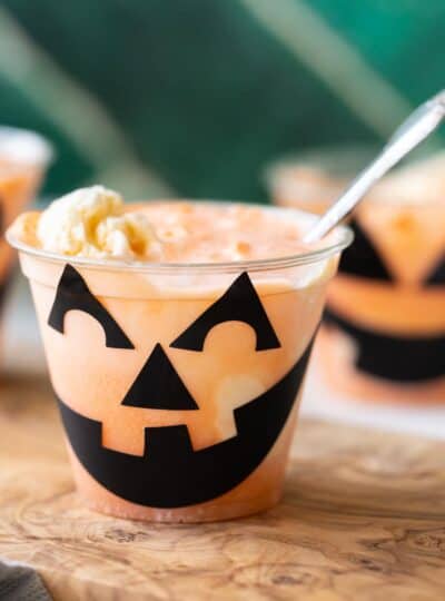 a jack o lantern float in a cup with orange soda and vanilla ice cream with spoon