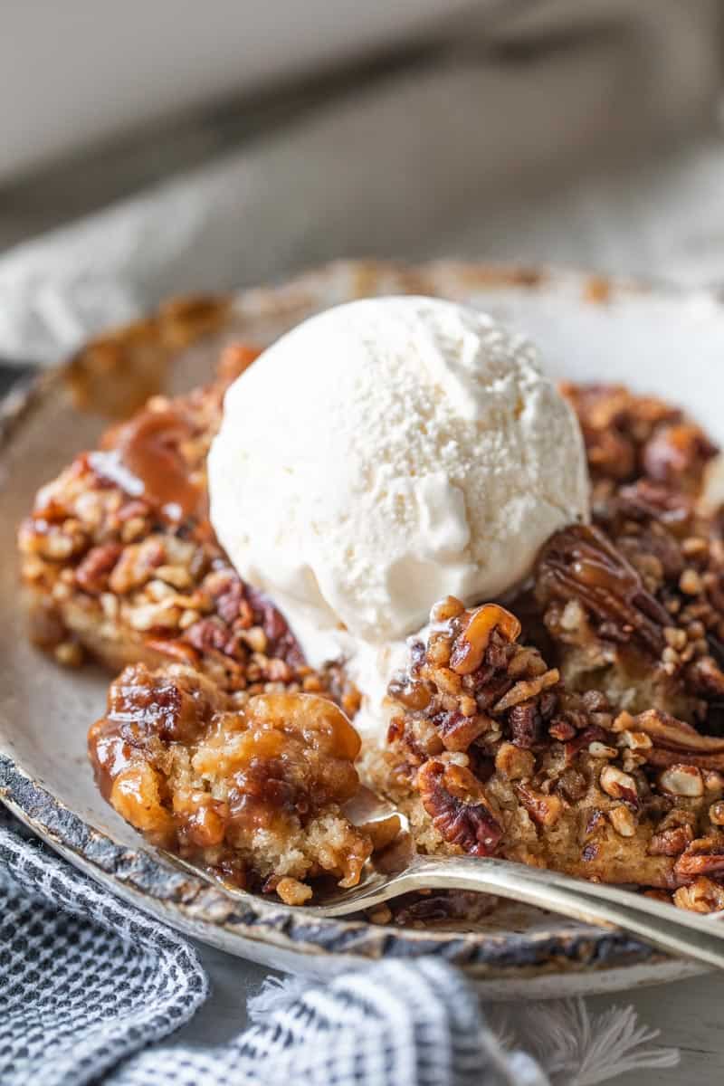 pecan pie cobbler in a bowl with vanilla ice cream on top