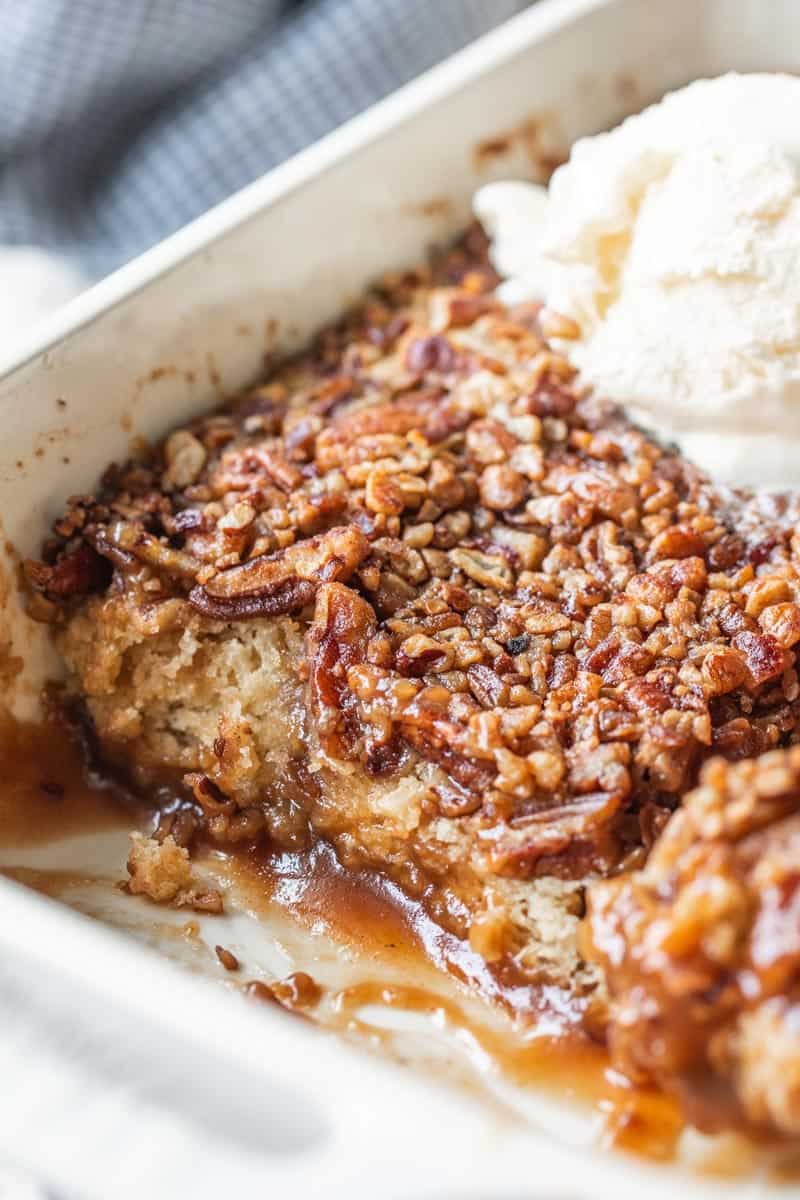 pecan pie cobbler in a baking pan with some removed showing the inside