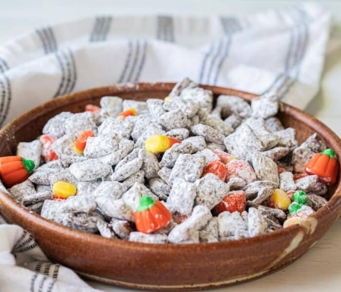 halloween muddy buddies in a bowl with candy corn and mallowcreme pumpkins