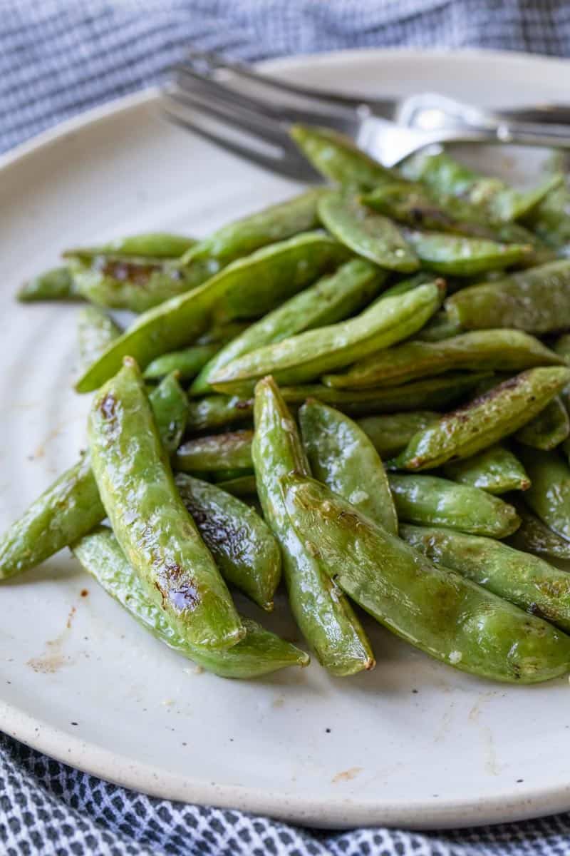close up view of roasted sugar snap peas on a plate