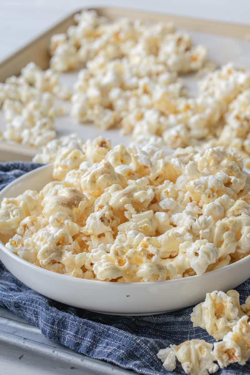 confetti popcorn in a large serving bowl next to a sheet pan filled with popcorn