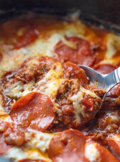 close up view of spoon scooping crockpot pizza casserole