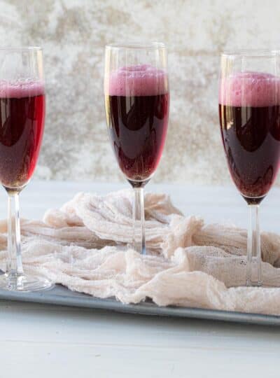 three glasses of a sparkling grape mocktail on a tray