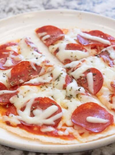 four slices of pepperoni pizza on a plate garnished with oregano