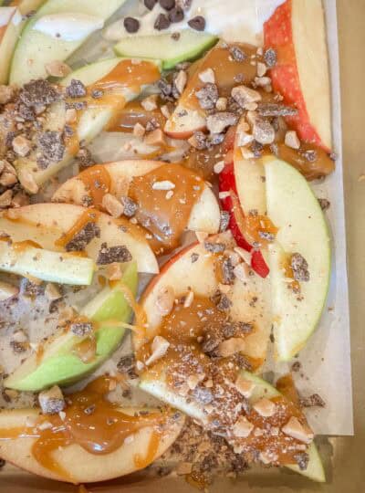apple slices with caramel and toffee bits on a baking tray