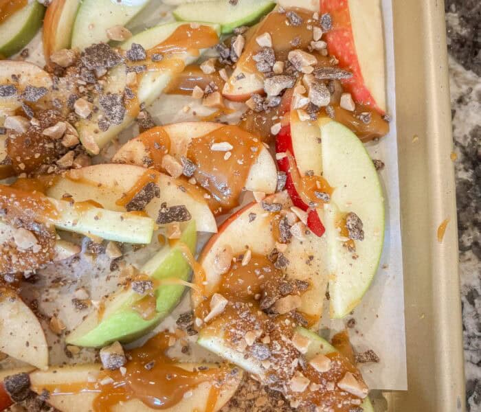 apple slices with caramel and toffee bits on a baking tray